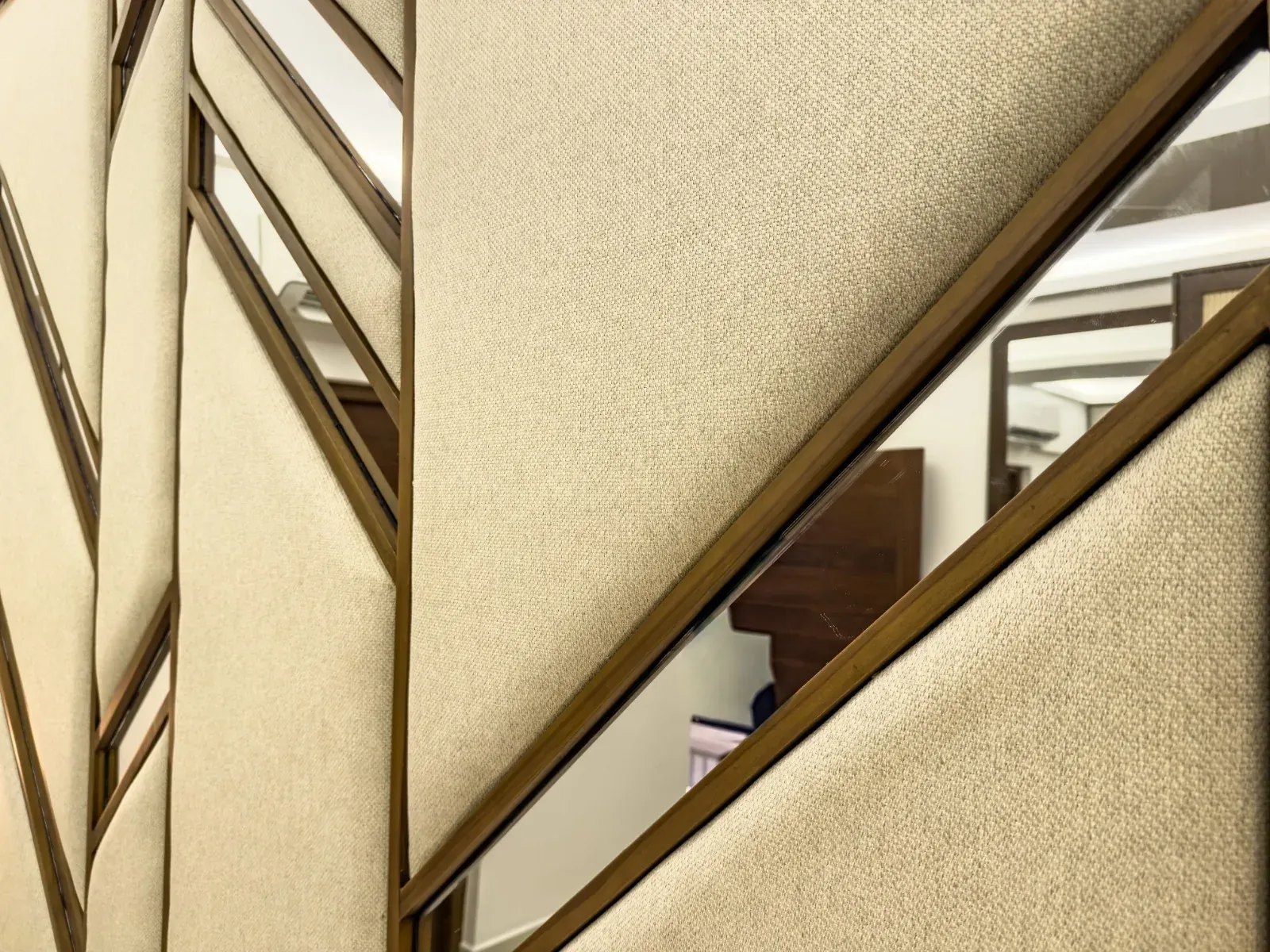 Close-up of the upholstered headboard showing angled mirror inlays set into the fabric panels