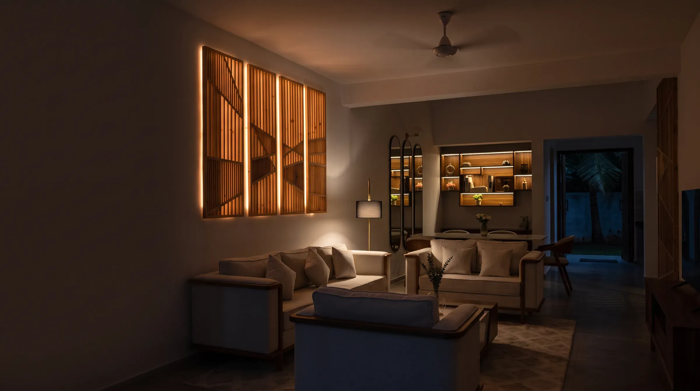 Warmly lit living room with backlit timber slat panels and oak-framed sofas