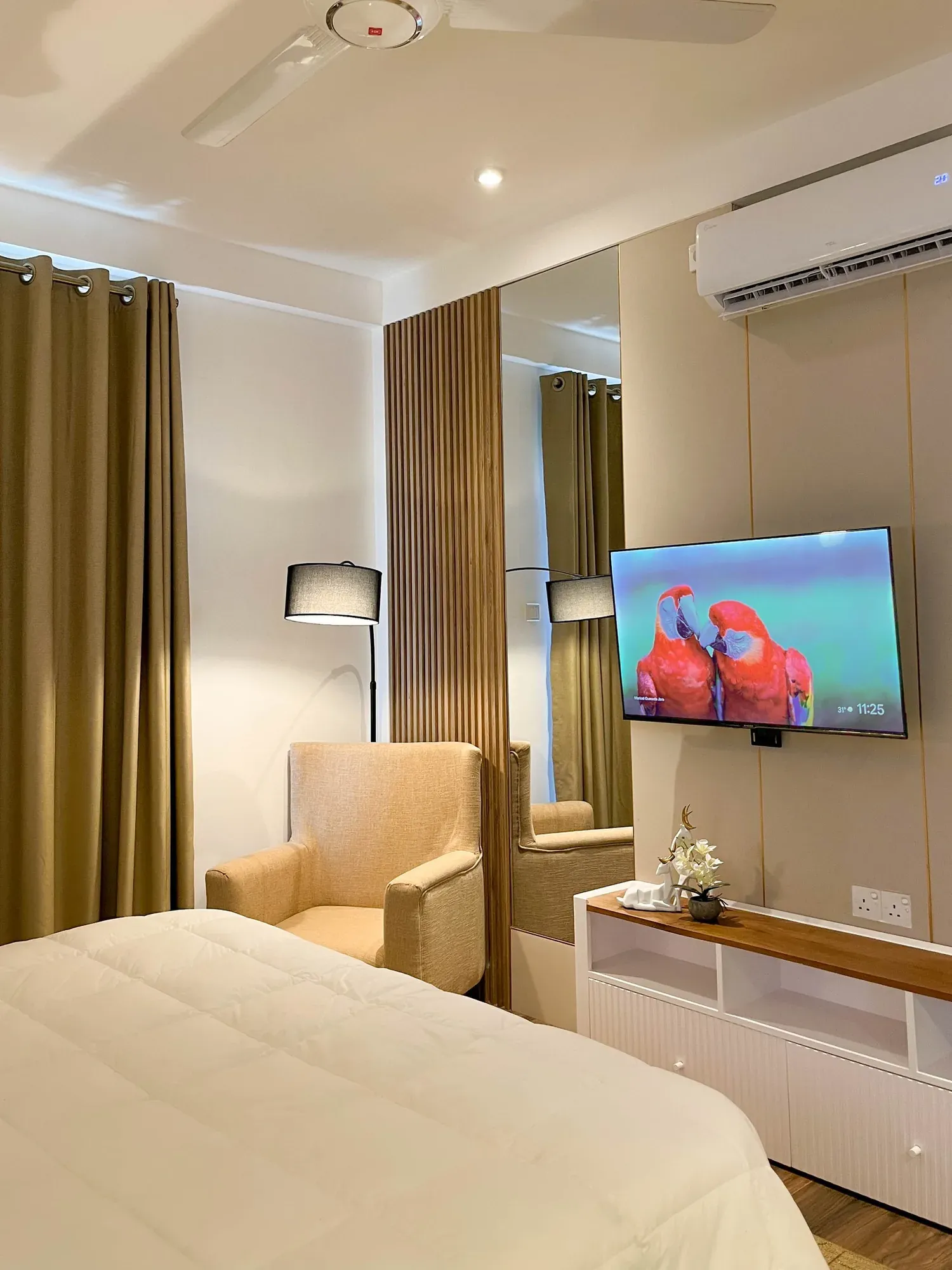 Bedroom TV wall with timber slats and a low white media unit