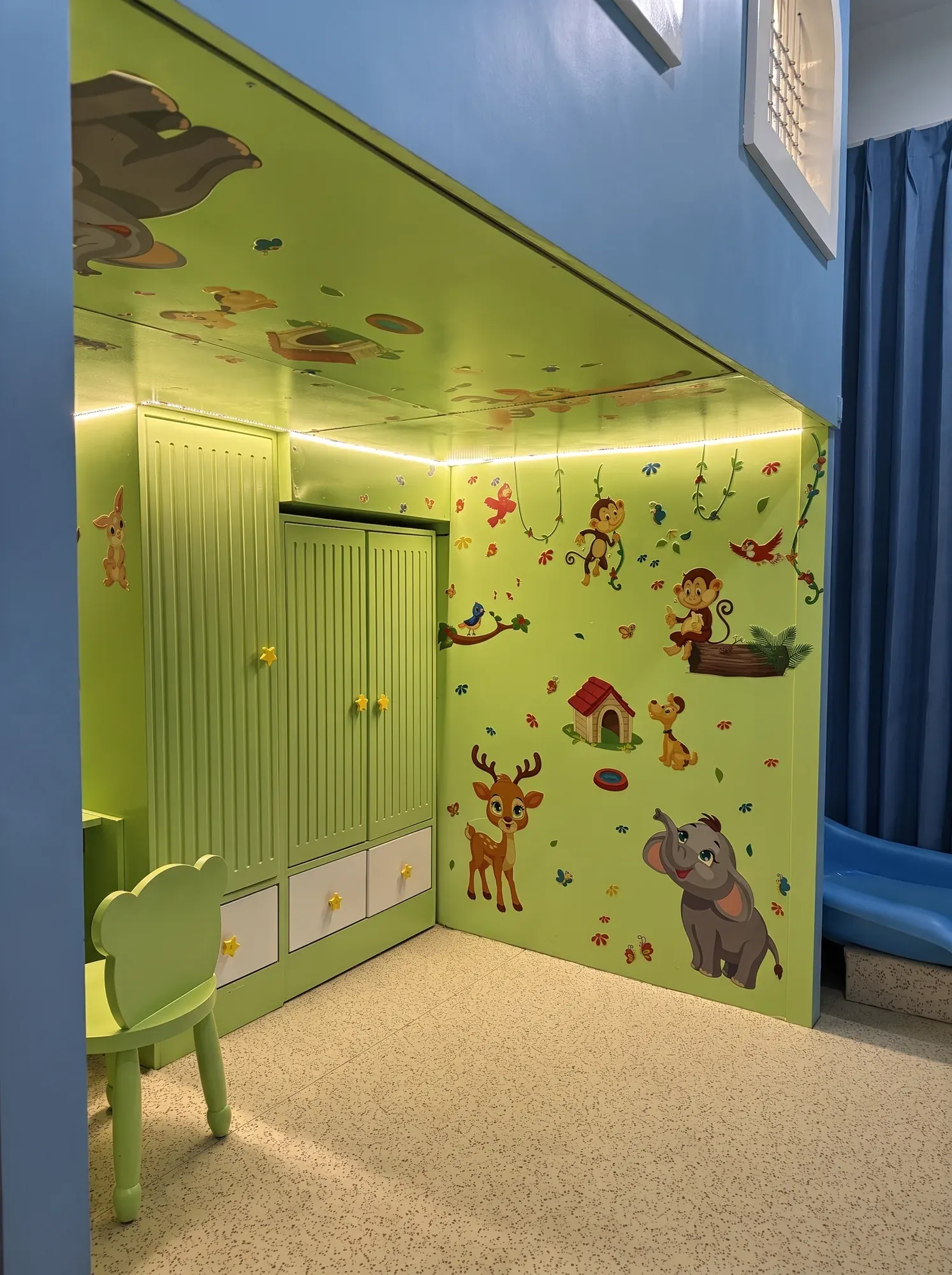 Kids' room with a custom green loft structure combining play space and storage